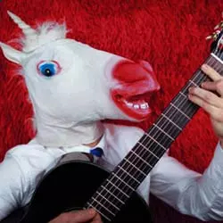 Imagem divertida de homem com máscara de unicórnio tocando violão.