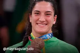 A imagem mostra a judoca brasileira Mayra Aguiar segurando a medalha de bronze, conquistada nos Jogos Olímpicos de Tóquio.