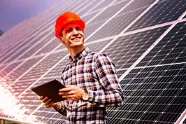 homem perto de placas de energia solar segurando um tablet