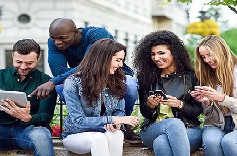 Imagem de jovens sorrindo enquanto navegam em diversos dispositivos móveis