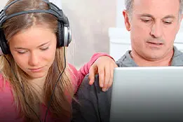 Um homem em frente ao computador e uma mulher com um fone no ouvido.