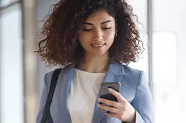 Imagem de uma mulher fazendo consultas no celular num ambiente de aeroporto.