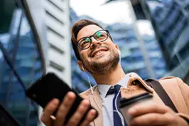 Imagem de um rapaz segurando um smartphone, com fones de ouvido.