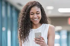 Imagem de um moça sorrindo usando o celular.