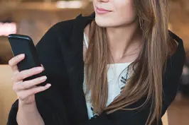 Imagem de uma mão de uma mulher segurando um smartphone.