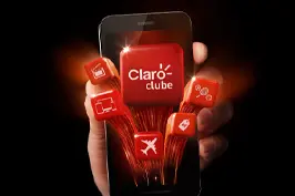 imagem com uma mão segurando um celular e na tela é apresentado o logo do Claro clube