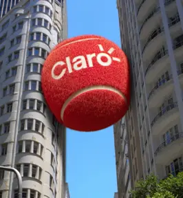Imagem de uma bola de tênis gigante com o logo da Claro entre dois prédios.