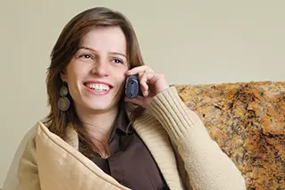 Foto mulher sentada no sofá falando ao telefone.