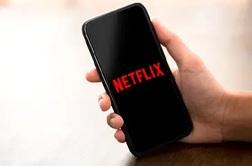 Mão segurando celular com logo Netflix.