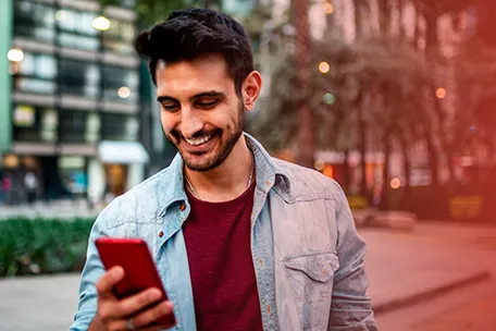 Imagem de um homem sorridente com um celular na mão.