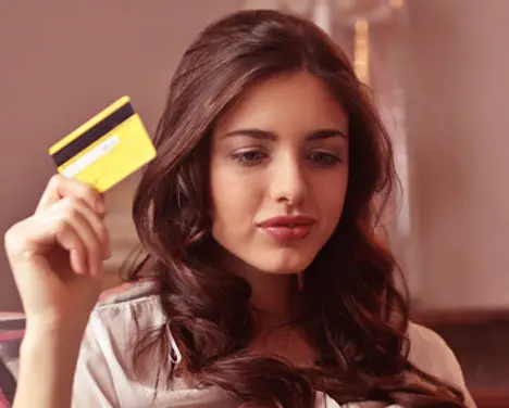 Uma moça segurando um cartão de crédito.