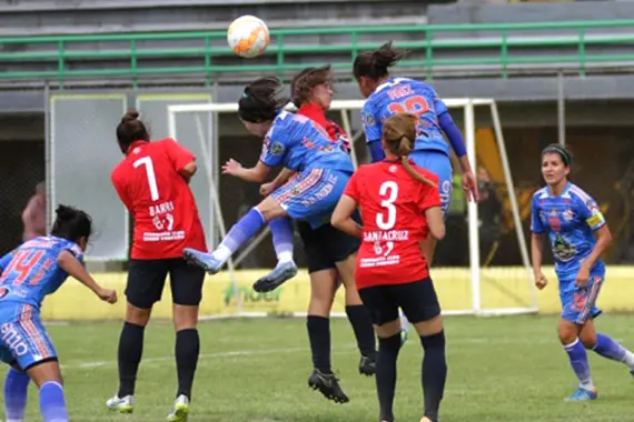 Imagem de jogadoras de futebol em disputa de bola aérea.