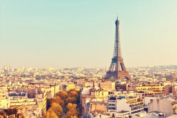 imagem: de Paris com algumas casas, prédios, rua com árvoes e a torre Eiffel em destaque.