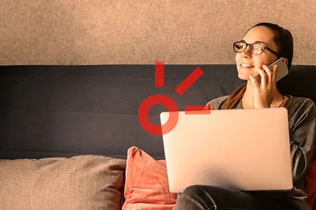 Imagem ilustrativa de uma mulher com computador e celular na mão.